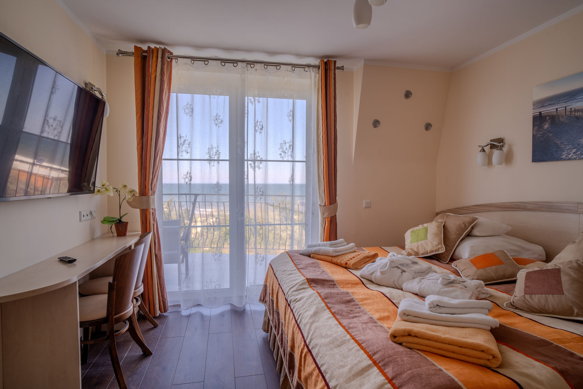 Przytulny pokój hotelowy z łóżkiem, biurkiem, telewizorem i balkonem z widokiem na morze