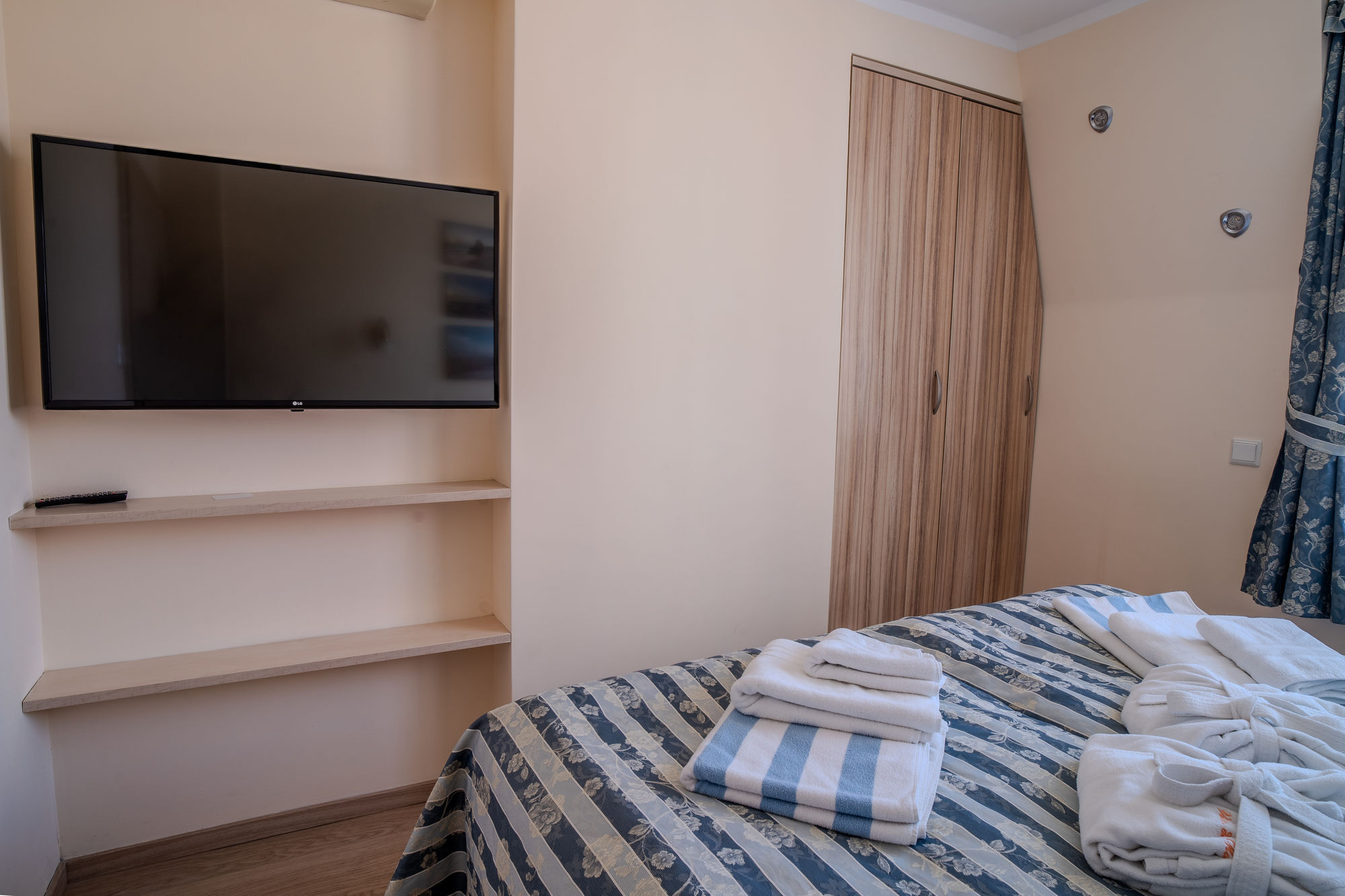 Pokój hotelowy z telewizorem, szafą i łóżkiem z ręcznikami